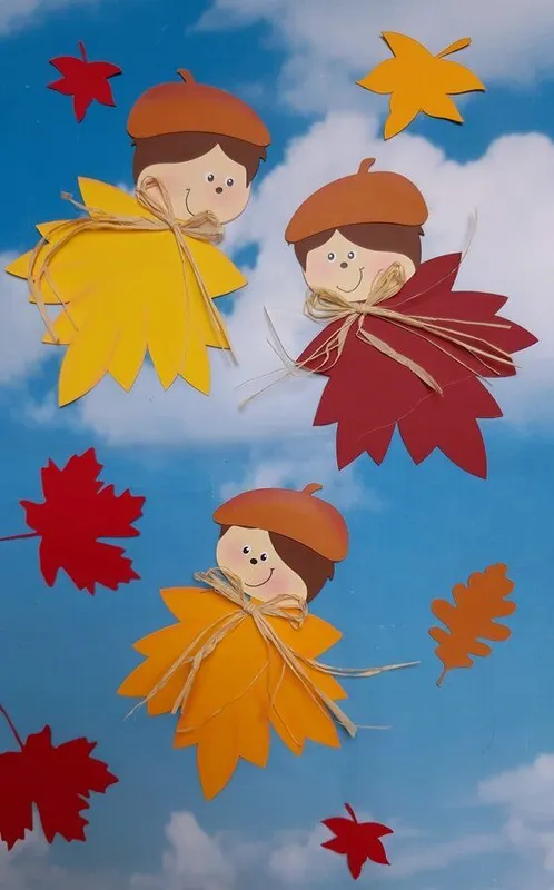 3 fertig gebastelte Blätterkinder mit einem Hintergrund vom Himmel.