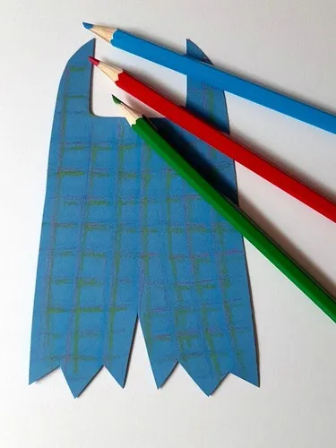 Ein Karomuster wird auf eine Hose aus Papier aufgemalt.