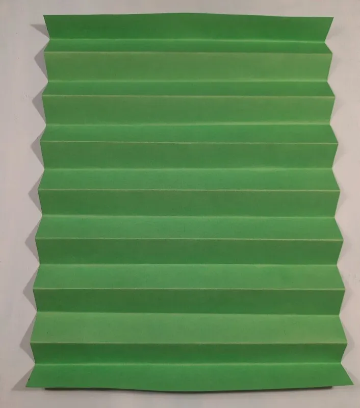 Die Faltungen vom Plissee auf grünem Papier.