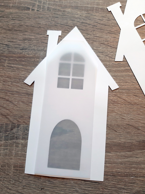 Ein Haus aus Bastelpapier wird mit Transparentpapier hinterlegt