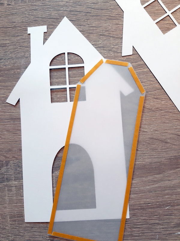 Ein Haus aus Bastelpapier wird mit Transparentpapier hinterklebt