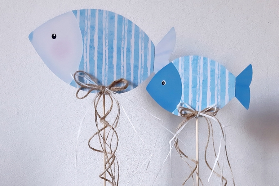 2 Fische aus Papier in blau und weiß am Holzstab