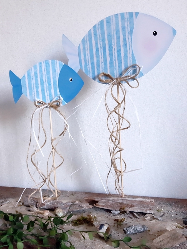 2 Fische aus Papier in blau und weiß am Holzstab