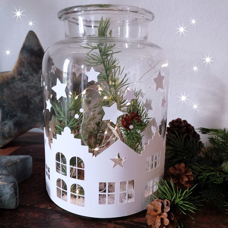 Beleuchtete Weihnachts-Vase mit einer Häuser-Bordüre und Tannenzweigen